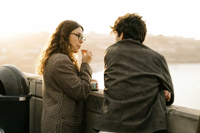 Couple standing side by side looking out over the water