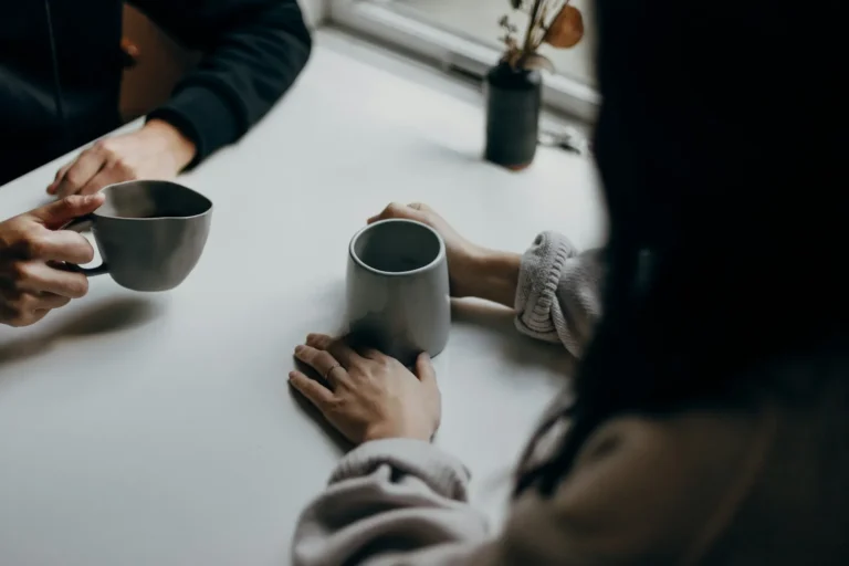 Two people talking over mugs of coffee