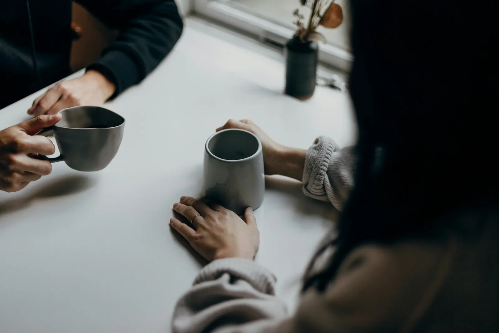 Two people talking over mugs of coffee