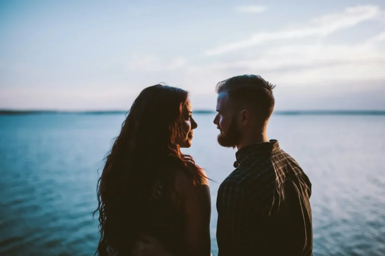 Couple facing each other beside a lake