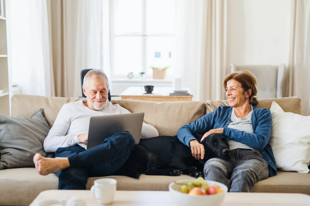 Older couple relaxing together on the sofa at home with their dog