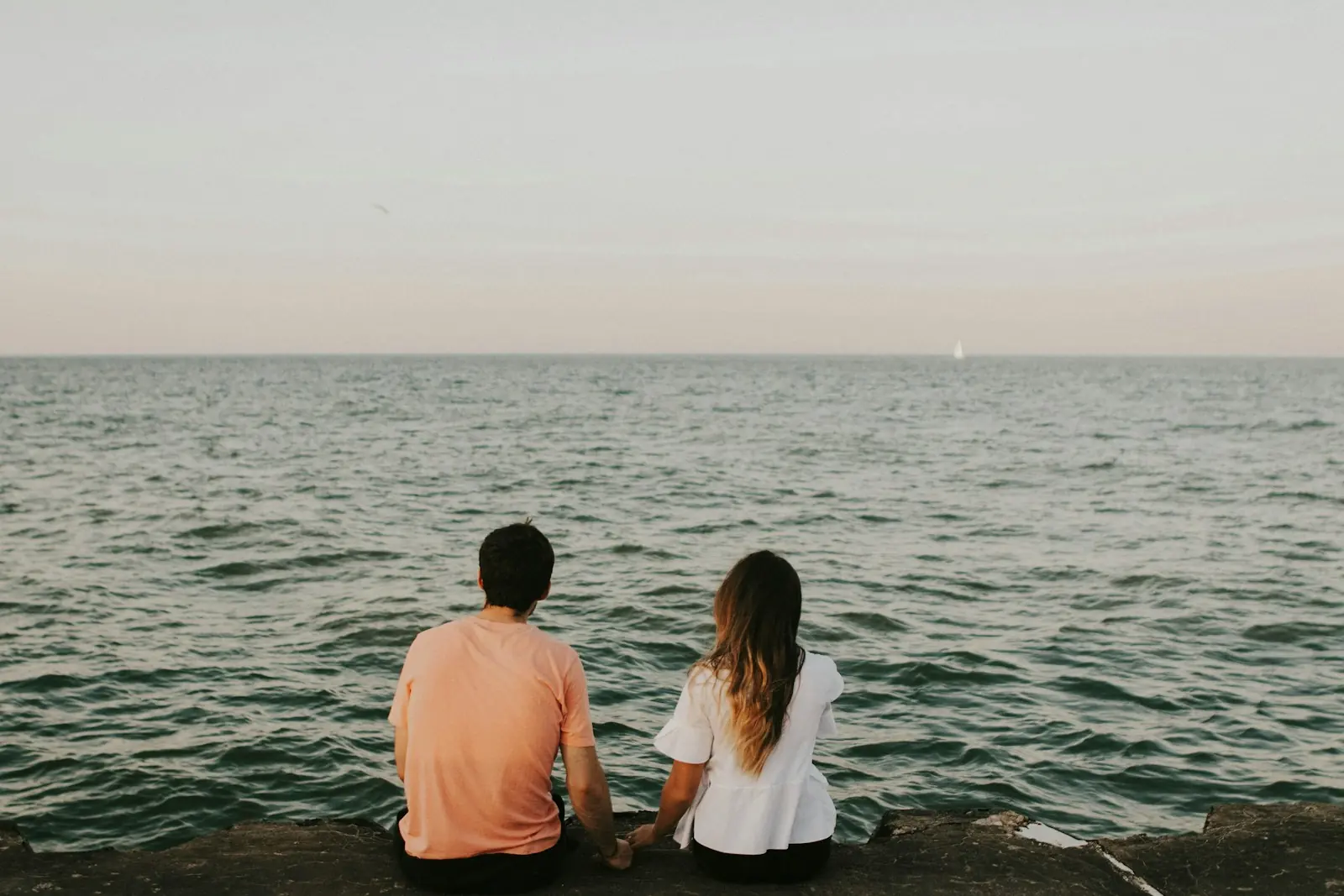 Couple sitting apart, looking out to sea