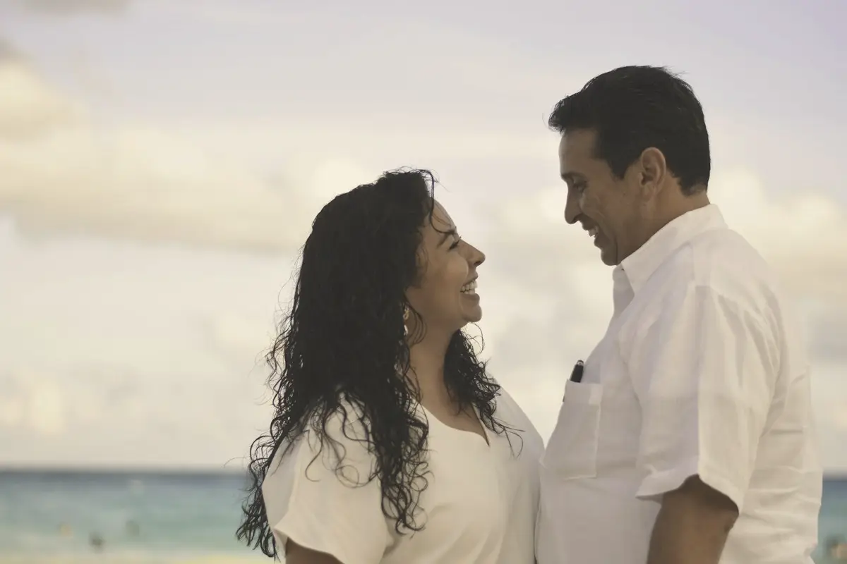 A couple in their forties talking and smiling by the sea