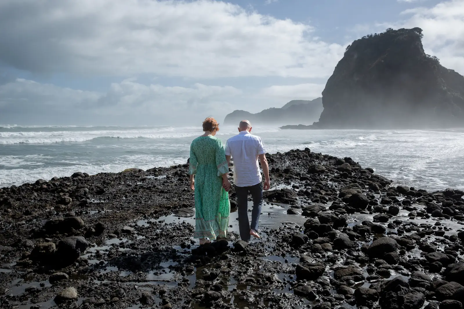 Tarisha and Mark walking along the rocks at Piha