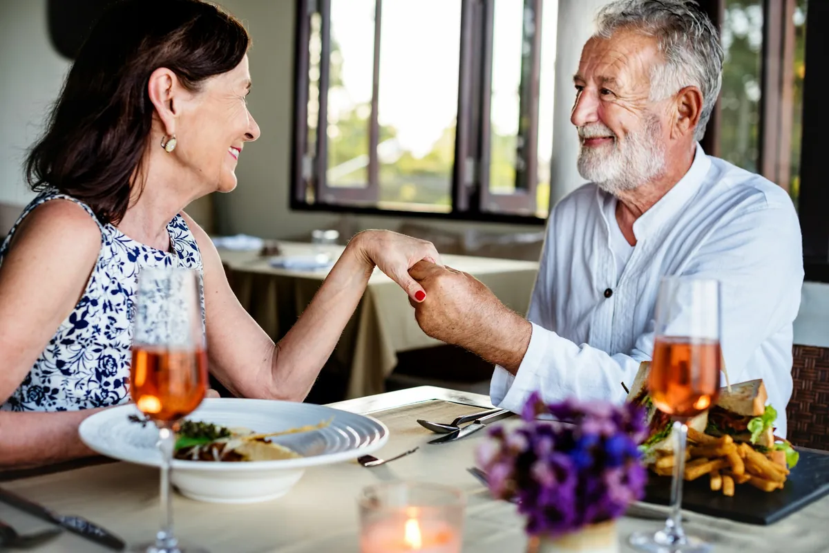 Mature couple holding hands at dinner table
