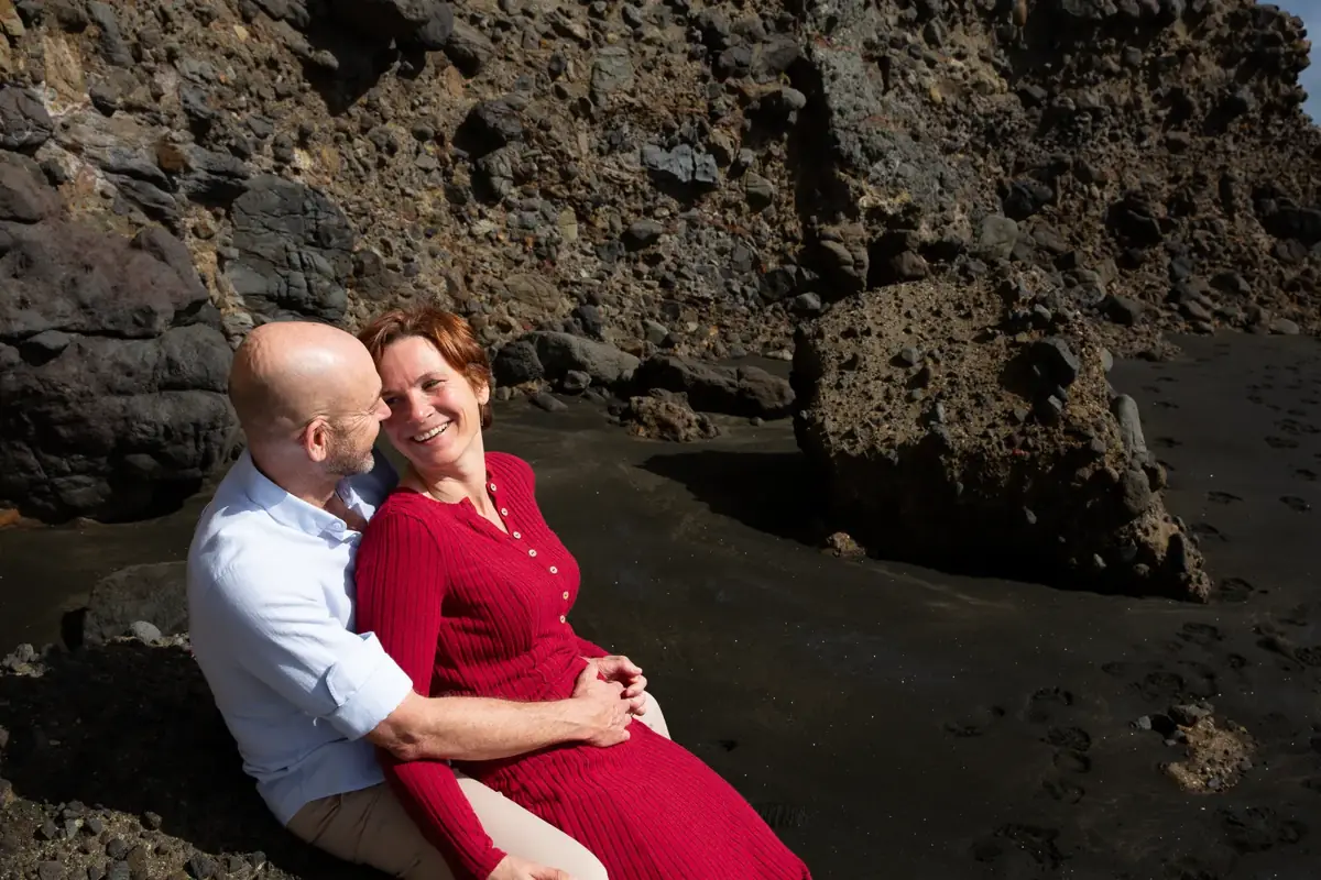 Mark and Tarisha looking at each other on the rocks at Piha