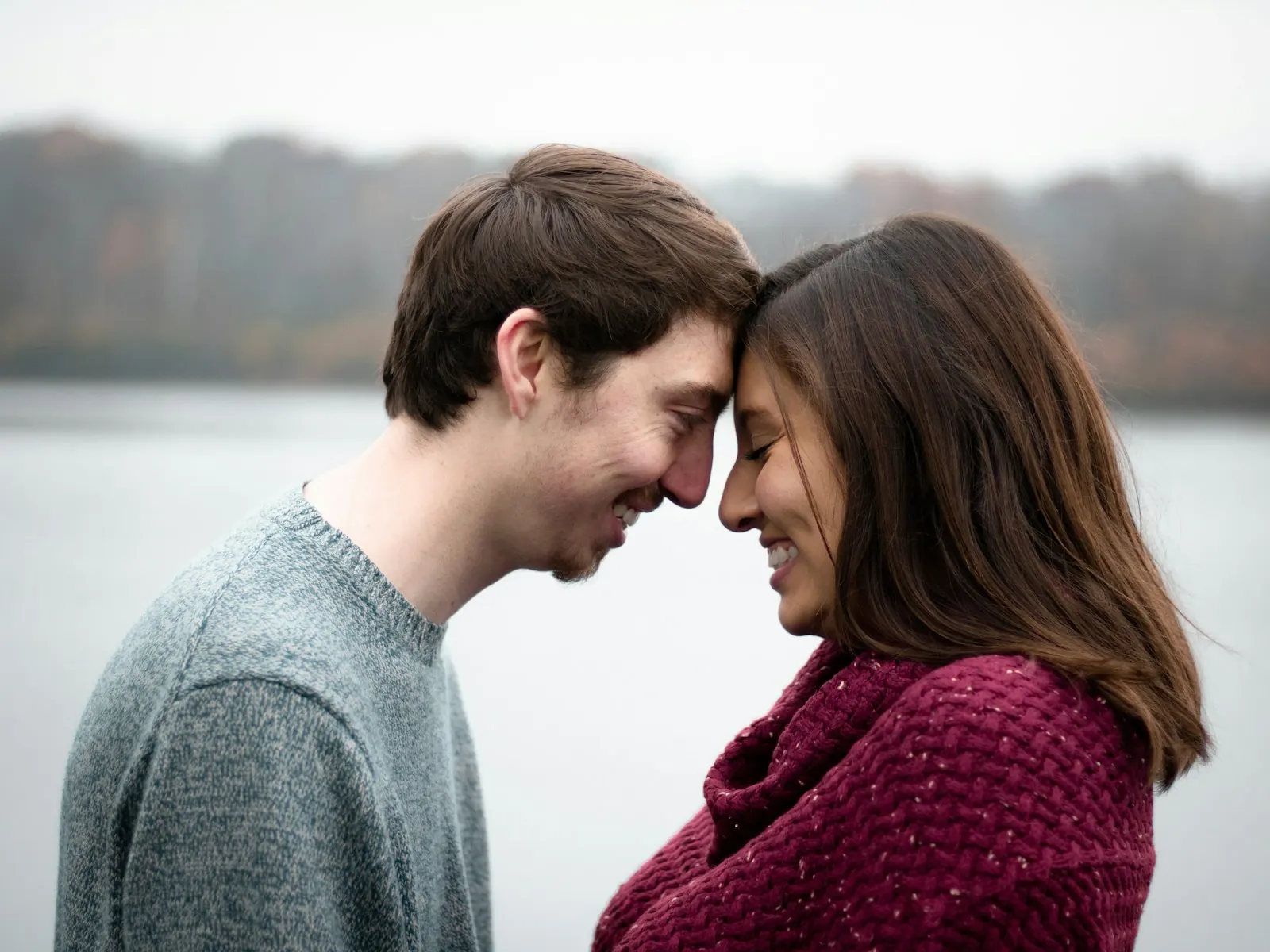 Couple resting their foreheads together by the water