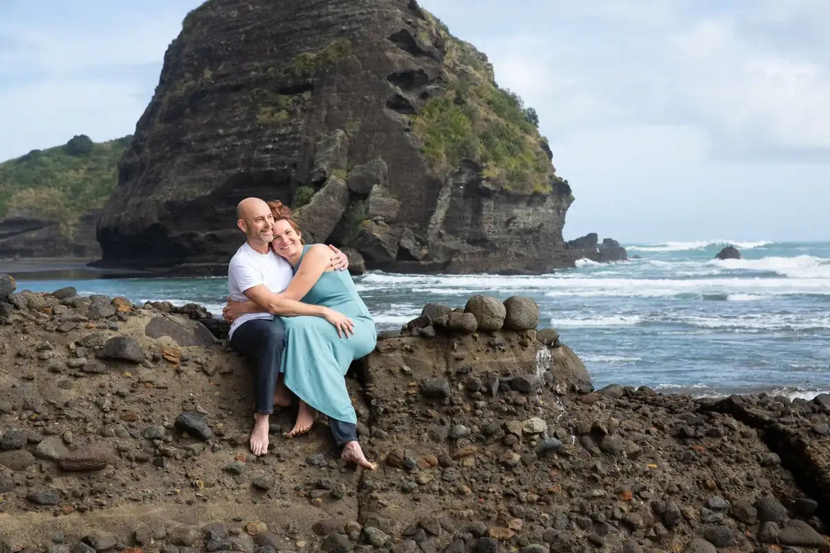 Tarisha and Mark sitting together by the sea at Piha