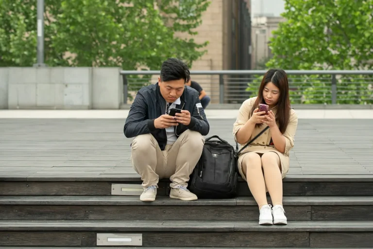 Couple sitting side by side, each on their phone