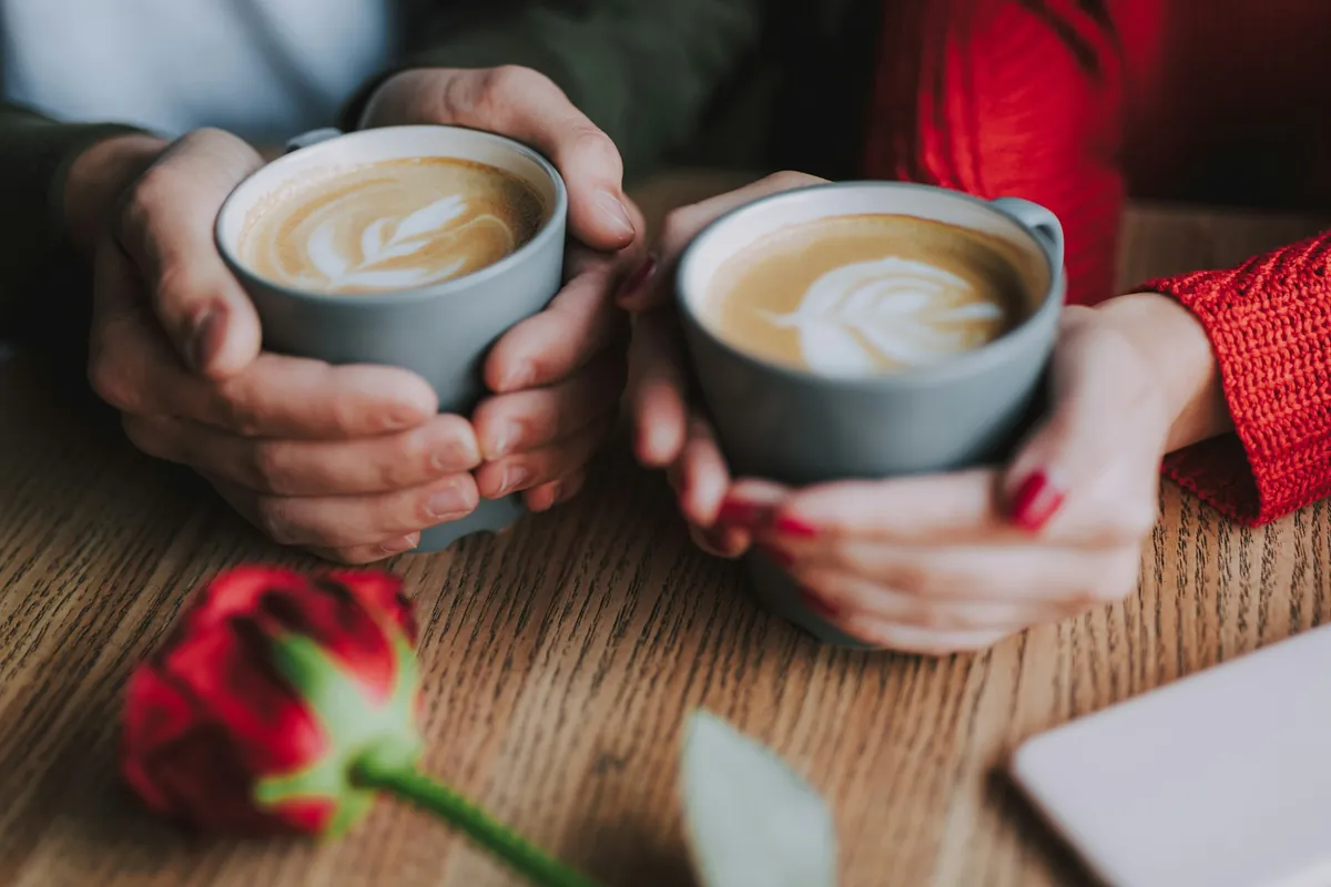 Two people holding coffee cups at a table