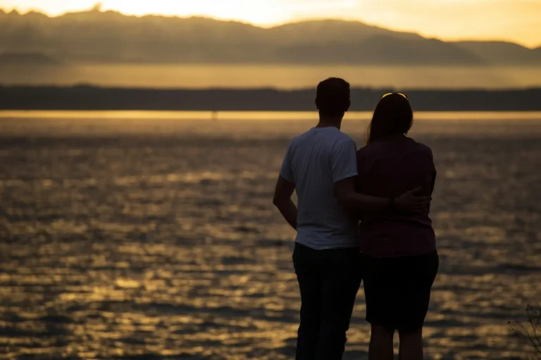 Couple with arms around each other at sunset