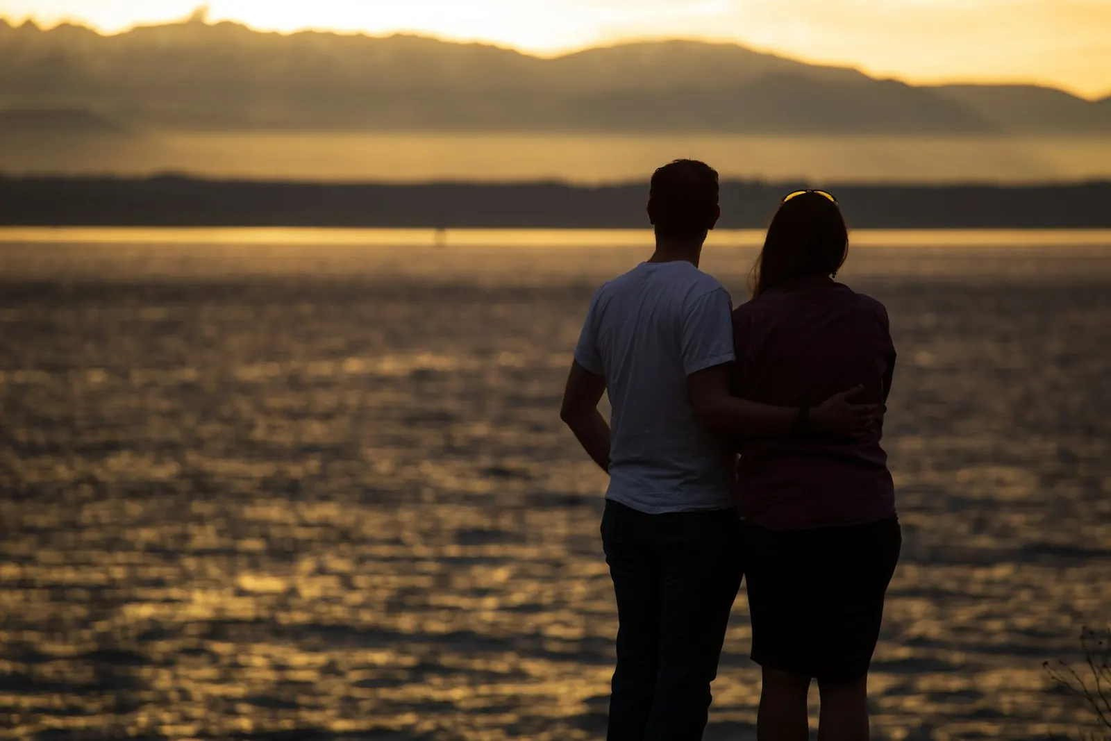 Couple with arms around each other at sunset