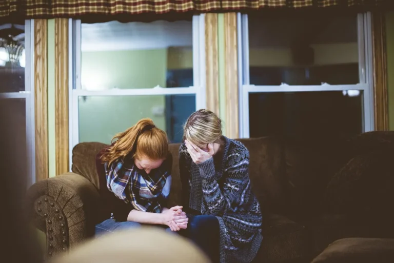 Couple sitting on the couch with their heads down