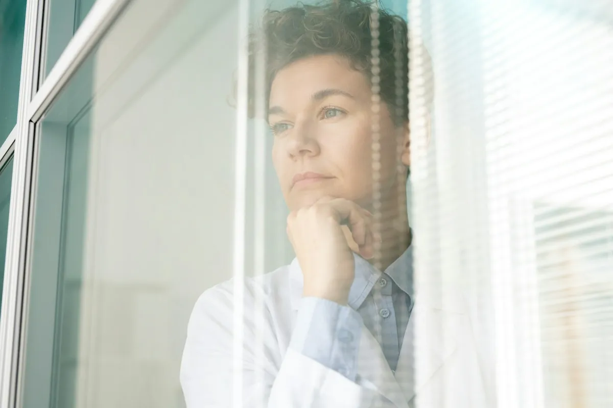 Woman looking out of a window, deep in thought
